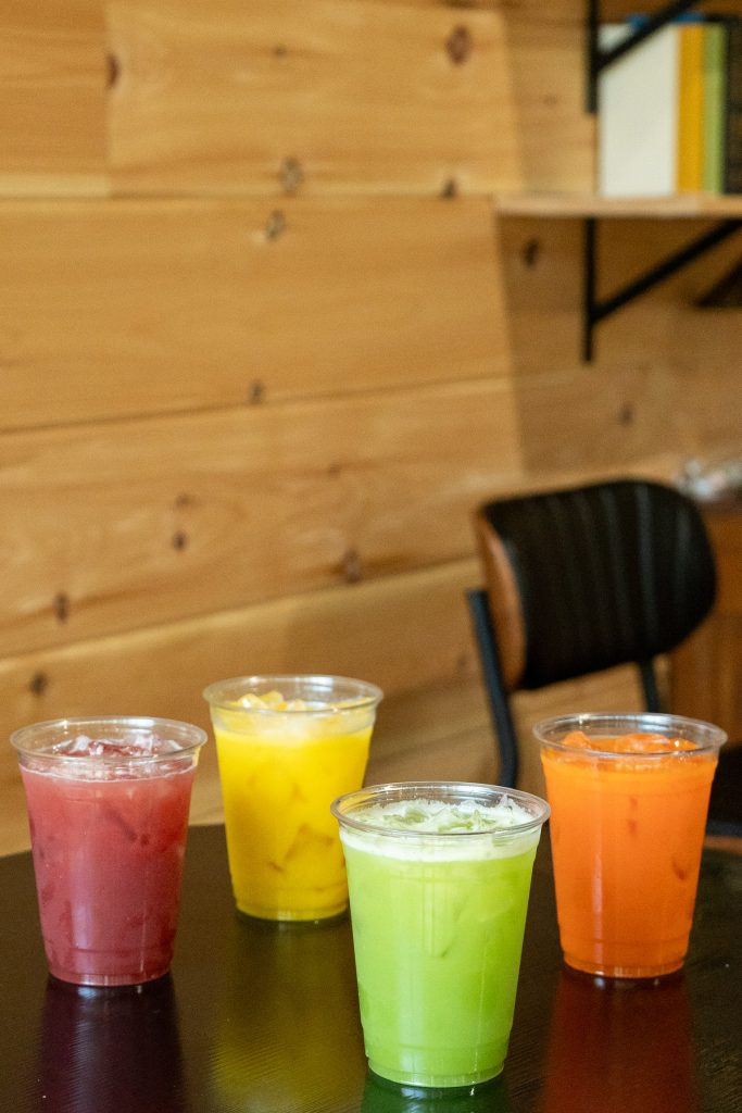 Four fresh pressed juices lined up on a table at Cafe Pilates